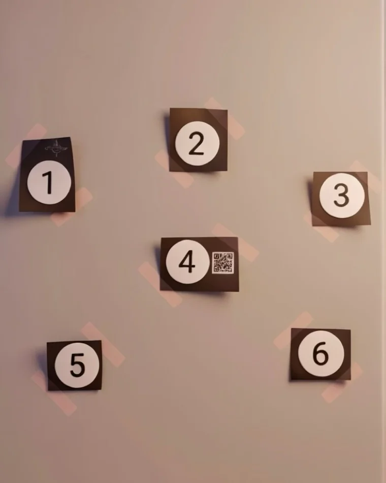 Six numbered paper circles cut out and taped to a wall, with a QR code beside circle four